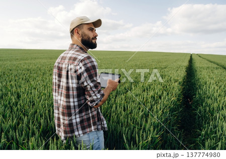 Quality control, with digital tablet. Man farmer is on the agricultural field Quality control, with digital tablet. Man farmer is on the agricultural field 137774980