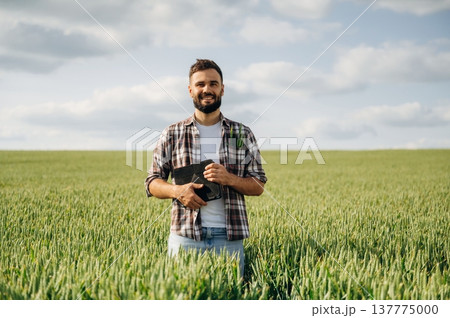 Positive facial expression, smiling. Man farmer is on the agricultural field 137775000