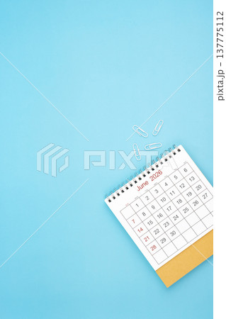 Desk calendar for June 2026 and white paper clip on a light blue background. Desk calendar for June 2026 and white paper clip on a light blue background. 137775112