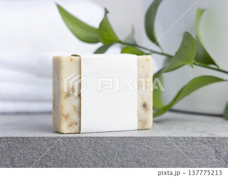 Soap bar with blank label against green leaves and white bath towels on grey stone, mockup Soap bar with blank label against green leaves and white bath towels on grey stone, mockup 137775213