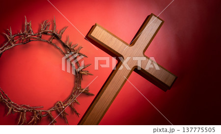 A symbolic wooden cross and crown of thorns set against a vibrant red background, representing the passion and sacrifice of Jesus Christ for Good Friday and Lent 137775505