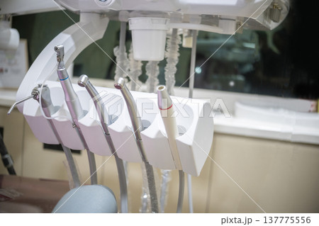A close-up view of various professional dental handpieces and tools organized in their holders on a modern dental unit in a clinical setting 137775556