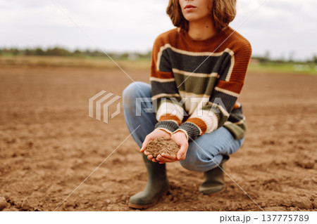 Close up of the female hands touching dry ground in an agricultural field while analyzing soil 137775789