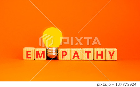 Empathy symbol. The concept word Empathy on wooden cubes. Beautiful white table. Beautiful orange background. Beautiful yellow light bulb. Copy space. Business, psychological and empathy concept. 137775924