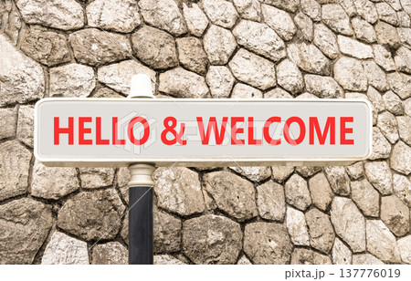 Hello and welcome symbol. Concept words Hello and welcome on beautiful big white road sign. Beautiful grey stone wall background. Business hello and welcome concept. Copy space. Hello and welcome symbol. Concept words Hello and welcome on beautiful big white road sign. Beautiful grey stone wall background. Business hello and welcome concept. Copy space. 137776019