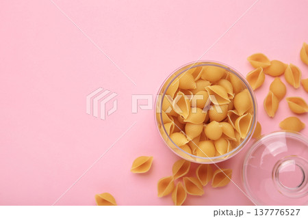 Conchiglie rigate. Raw striped shell pasta in jar on pink background Conchiglie rigate. Raw striped shell pasta in jar on pink background 137776527