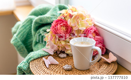 Home composition with a cup of coffee, flowers and a knitted element. 137777810