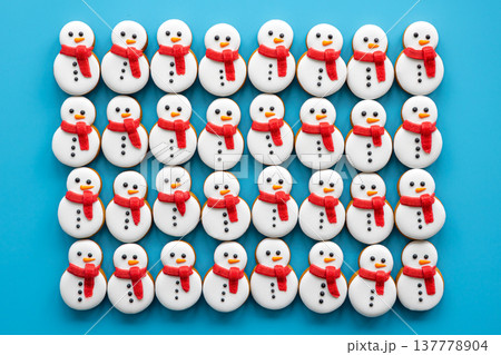 Gingerbread snowmen covered with icing on a blue background, flat lay. Gingerbread snowmen covered with icing on a blue background, flat lay. 137778904