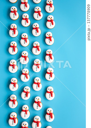 Gingerbread snowmen covered with icing on a blue background, flat lay. Gingerbread snowmen covered with icing on a blue background, flat lay. 137778909
