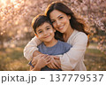 Happy mother and son hugging under blooming cherry blossoms in spring park 137779537