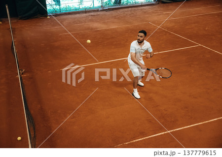 Top down view. Man is playing tennis indoors in the hangar Top down view. Man is playing tennis indoors in the hangar 137779615