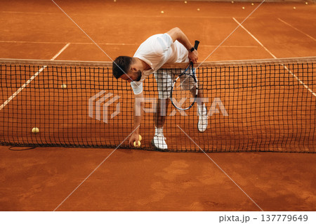 Front view. Man is playing tennis indoors in the hangar Front view. Man is playing tennis indoors in the hangar 137779649