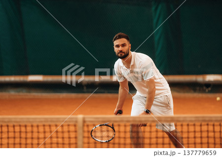 Front view. Man is playing tennis indoors in the hangar Front view. Man is playing tennis indoors in the hangar 137779659