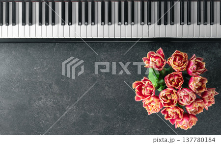 Piano keyboard and a bouquet of flowers on a dark textured background, top view. 137780184