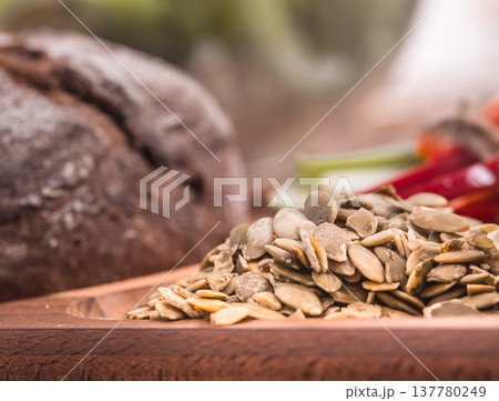 Pumpkin seeds close-up on a wooden plate Pumpkin seeds close-up on a wooden plate 137780249