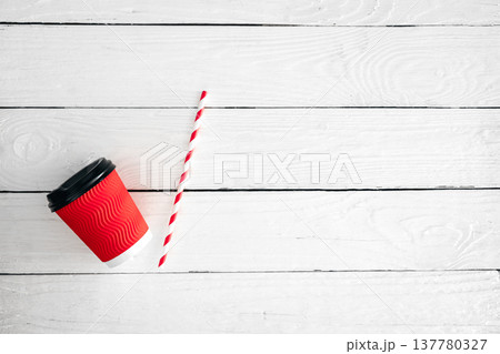 Red paper cup and straw for drinks on a white wooden background. Red paper cup and straw for drinks on a white wooden background. 137780327