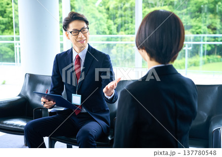 明るいラウンジで商談・提案をする笑顔のビジネスマンと女性 137780548