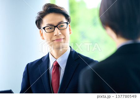 明るいラウンジで商談・提案をする笑顔のビジネスマンと女性 137780549