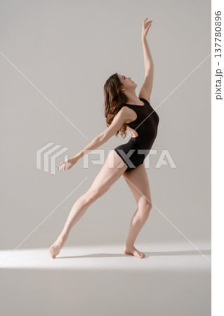Young woman performing a graceful contemporary dance movement in a minimalist studio. 137780896