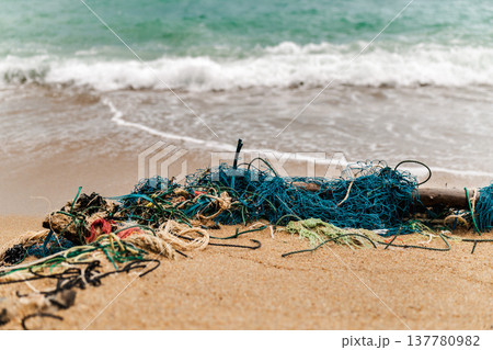 Abandoned fishing nets and ropes washed onto sandy beach with ocean waves Koh Samui Thailand Abandoned fishing nets and ropes washed onto sandy beach with ocean waves Koh Samui Thailand 137780982