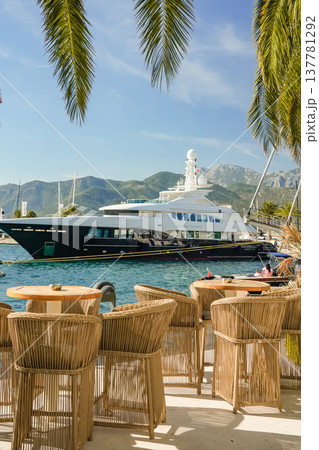 View of Yacht from Outdoor Cafe with Wicker Furniture and Palm Leaves View of Yacht from Outdoor Cafe with Wicker Furniture and Palm Leaves 137781292