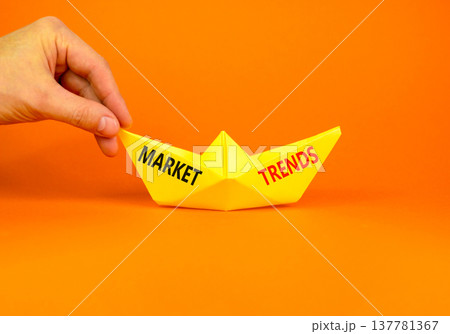 Market trends words symbol. Concept words Market trends on beautiful yellow paper boat. Beautiful orange background. Businessman hand. Business and Market trends words concept. Copy space. 137781367