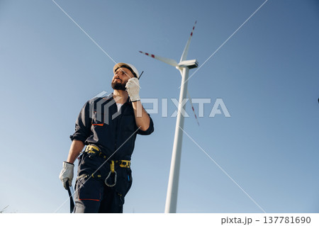Speaking by walkie talkie. Engineer in field checking on wind turbine production 137781690