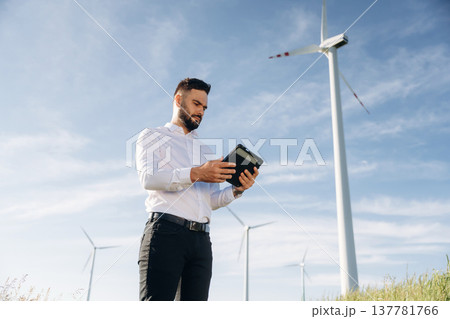 Digital tablet in hands. Engineer in field checking on wind turbine production 137781766