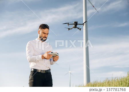 Controlling the drone. Engineer in field checking on wind turbine production Controlling the drone. Engineer in field checking on wind turbine production 137781768