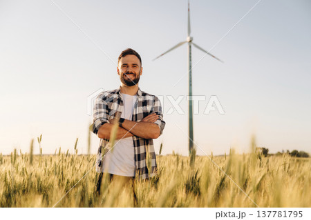 In checkered shirt. Guy engineer in wheat field against wind turbines 137781795