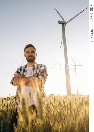 Beautiful nature. Guy engineer in wheat field against wind turbines 137781807