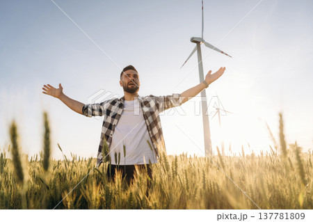 Freedom conception. Guy engineer in wheat field against wind turbines 137781809