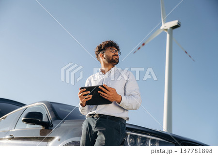 Male engineer in field checking on wind turbine production 137781898