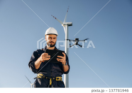 Engineer in field checking on wind turbine production Engineer in field checking on wind turbine production 137781946