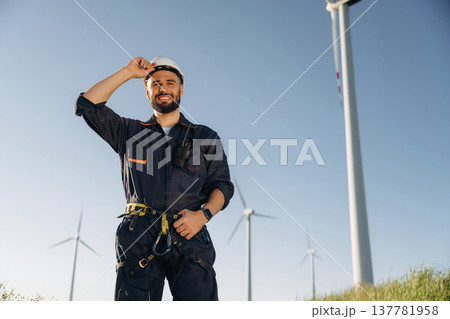 Employee is standing and posing. Engineer in field checking on wind turbine production Employee is standing and posing. Engineer in field checking on wind turbine production 137781958