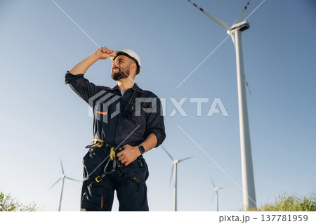 Employee is standing and posing. Engineer in field checking on wind turbine production Employee is standing and posing. Engineer in field checking on wind turbine production 137781959