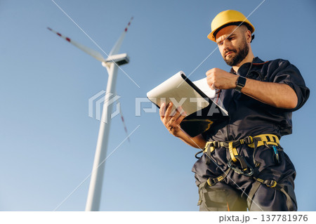 Documents in notepad. Engineer in field checking on wind turbine production 137781976