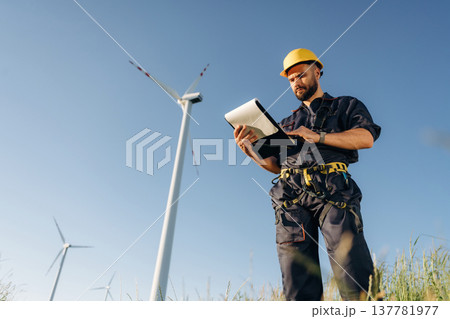 Documents in notepad. Engineer in field checking on wind turbine production Documents in notepad. Engineer in field checking on wind turbine production 137781977