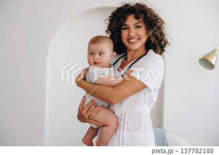 Professional medical worker. Female doctor is with newborn baby indoors Professional medical worker. Female doctor is with newborn baby indoors 137782180