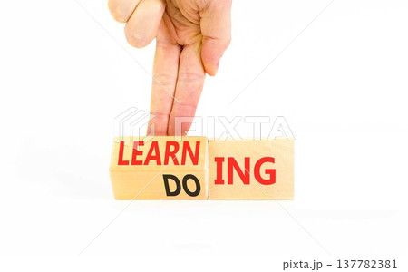 Doing or learning symbol. Concept words Doing to Learning on beautiful wooden cubes. Beautiful white background. Businessman's hand. Educational business doing or learning concept. Copy space 137782381