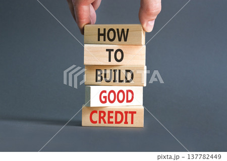 How to build good credit symbol. Concept words How to build good credit on beautiful wooden blocks. Beautiful grey background. Businessman hand. Business how to build good credit concept. Copy space 137782449
