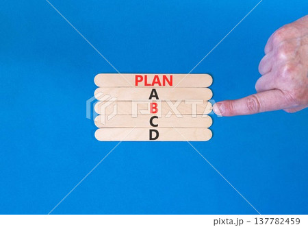 Time to plan B symbol. Concept word Plan A B C D on beautiful wooden sticks. Businessman's hand. Beautiful blue background. Business planning and time to plan B concept. Copy space. Time to plan B symbol. Concept word Plan A B C D on beautiful wooden sticks. Businessman's hand. Beautiful blue background. Business planning and time to plan B concept. Copy space. 137782459