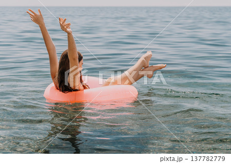 Woman floating inner tube water arms raised summer vacation sea 137782779
