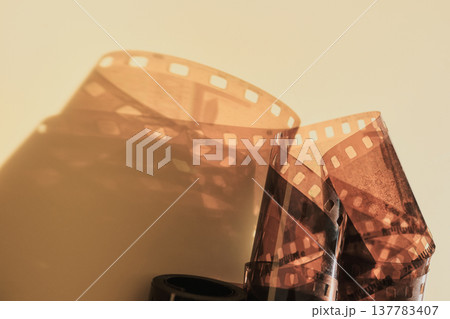 Rolled 35mm film negatives showing perforated edges and casting warm shadow 137783407