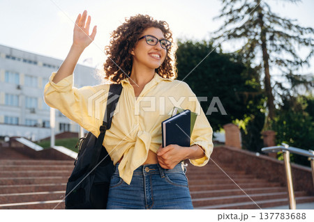Hello hand gesture. Beautiful woman student is near the university outdoors Hello hand gesture. Beautiful woman student is near the university outdoors 137783688