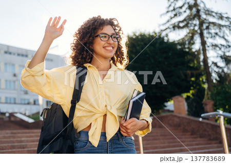 Hello hand gesture. Beautiful woman student is near the university outdoors 137783689