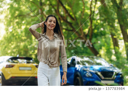 Posing for the camera. Young woman is in the forest with two cars Posing for the camera. Young woman is in the forest with two cars 137783984