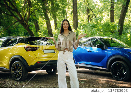 Hands to the side, the choice. Young woman is in the forest with two cars Hands to the side, the choice. Young woman is in the forest with two cars 137783998