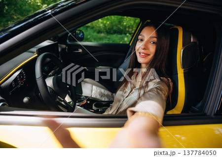Side view, driver is sitting. Woman is with her car in the forest 137784050