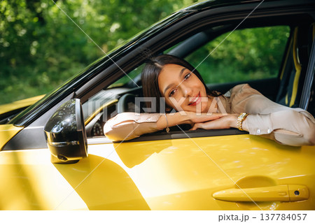 Break from driving, sitting and looking through the opened window. Woman is with her car in the forest Break from driving, sitting and looking through the opened window. Woman is with her car in the forest 137784057